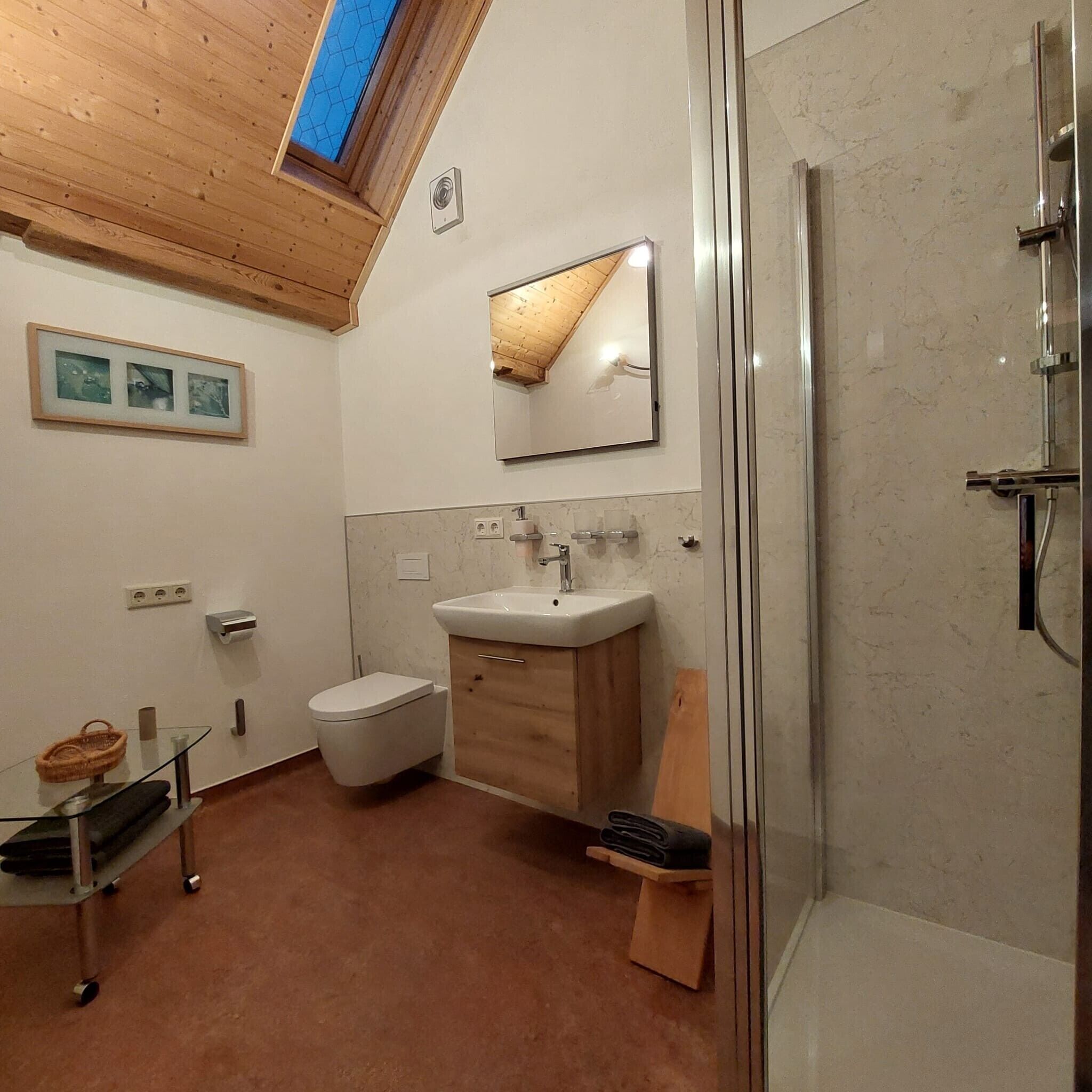 Un baño con inodoro, lavamanos, espejo y ducha.