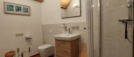 Un baño con inodoro, lavamanos, espejo y ducha.