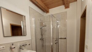 Ein Badezimmer mit einem Holzbettchen, einer Duschkabine aus Glas und einem Spiegel.