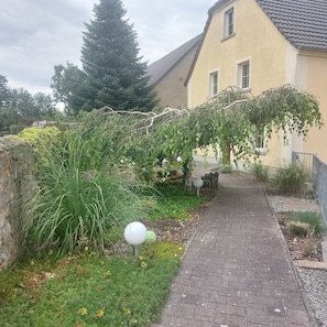Un chemin pavé mène à un bâtiment doté d’un toit en pente et d’un mur en pierre sur l’un de ses côtés.