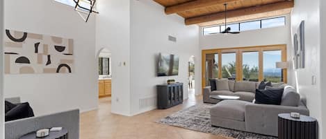 A spacious living area with a high ceiling, a large window, and a modern fireplace.