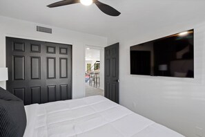 A bedroom with a bed, a ceiling fan, a TV, and a door leading to a balcony. - Foothills Oasis Heated Pool&HotTub Stunning Views (Tucson)
