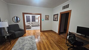 A living room with a sofa, a desk with a computer, a lamp, and a rug.