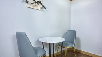 A corner room with two grey chairs, a small white table, and a wall-mounted art piece.