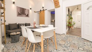 A dining area with a white table and chairs, a grey sofa, and a patterned floor.