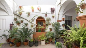 A courtyard with various potted plants and a central archway.
