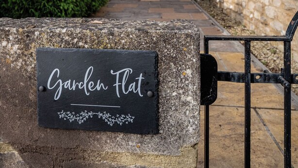 A stone building with a sign reading "Garden Flat." - Garden Flat Apartment in Grosvenor Place (Bath)