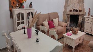 Ein gemütliches Wohnzimmer mit einem beigen Sofa, einem weißen Tisch und einem Kamin aus Stein.
