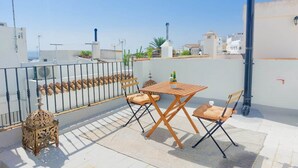 A rooftop terrace with a table and chairs, a decorative lantern, and a view of the cityscape.