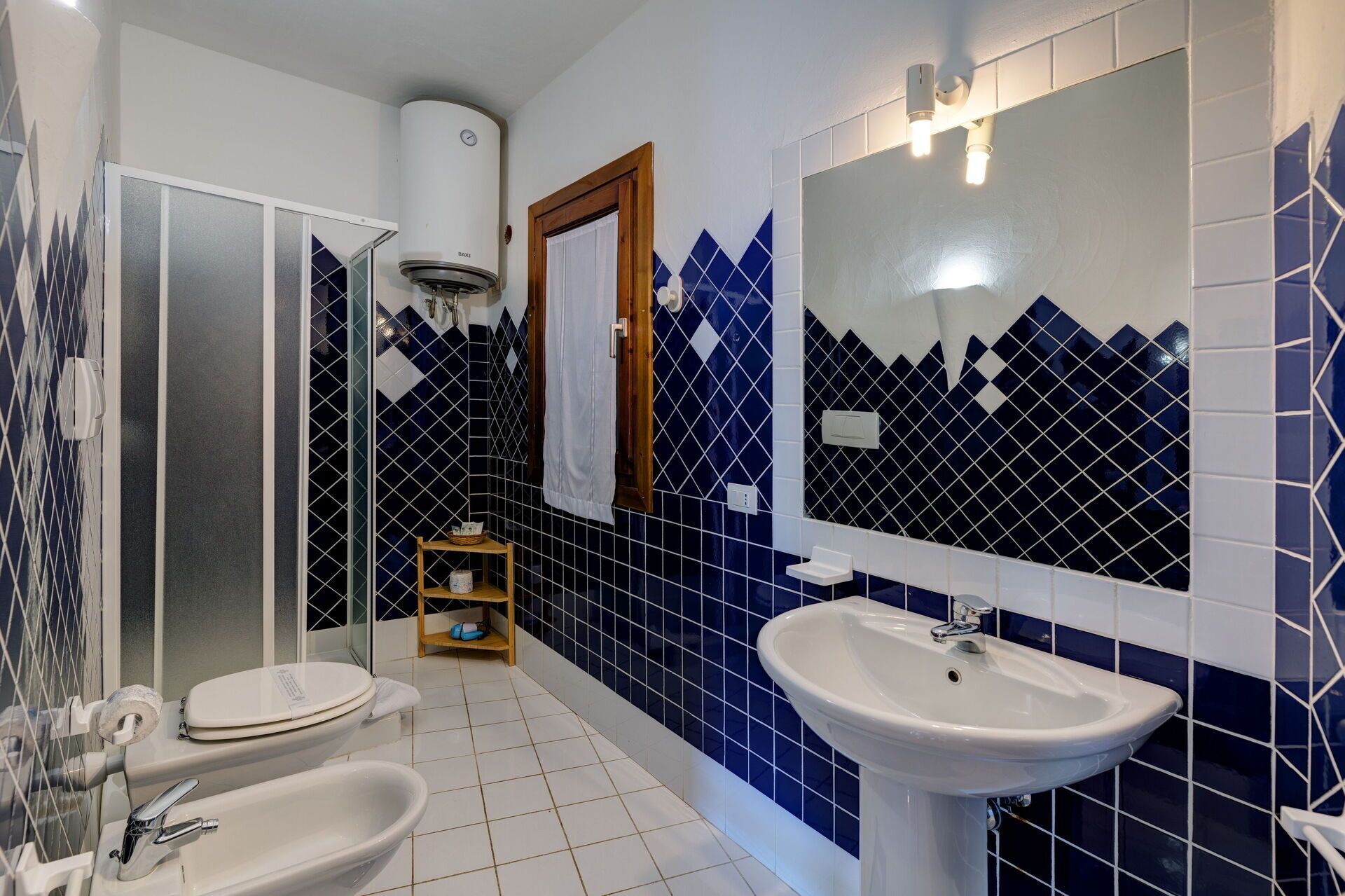 Une salle de bain avec des toilettes blanches, un lavabo blanc et un miroir.