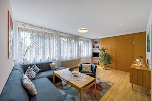 A living room with a sofa, a coffee table, a chair, a plant, and a cabinet.
