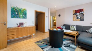 A modern living room with a sofa, a coffee table, a cabinet, and artwork on the walls.