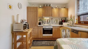 A compact kitchen with wooden cabinets, a microwave, a stove, and a sink.