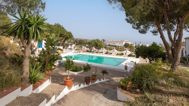 A swimming pool surrounded by potted plants and trees, with a view of buildings in the background. - Almarchada 38 - Villa With Private Pool In Mijas (, Málaga)