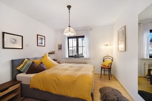 A bedroom with a bed, a chair, a window, and a radiator.