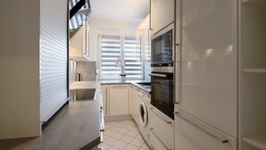 A compact kitchen with a washing machine, oven, and microwave.