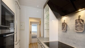 A modern kitchen with a built-in oven, a stovetop, and a glass door leading to a dining area.