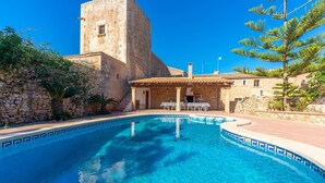 Una piscina con paredes de piedra y una torre de piedra al fondo.