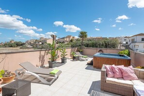 Eine Dachterrasse mit Liegestühlen, einem Whirlpool und Pflanzen in Töpfen.