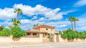 A two-story house with a tiled roof, surrounded by greenery and palm trees. - Es Garroveret - Villa With Private Pool. Free Wifi (, Illes Balears)