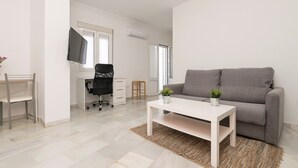 A modern living room with a grey sofa, a white coffee table, and a TV mounted on the wall.