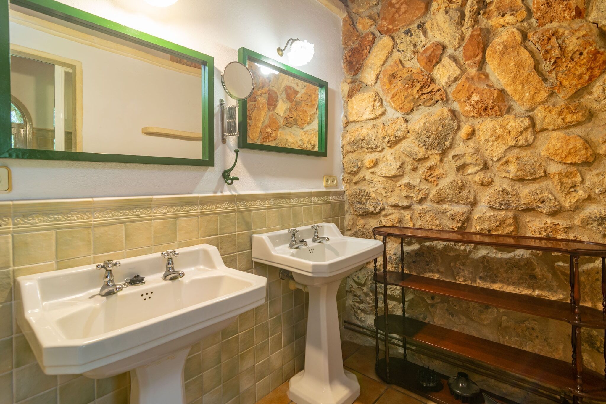 Un baño con dos lavamanos, un espejo y una pared de piedra.