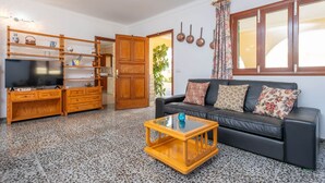 A living room with a black leather sofa, wooden entertainment unit, and a glass coffee table.