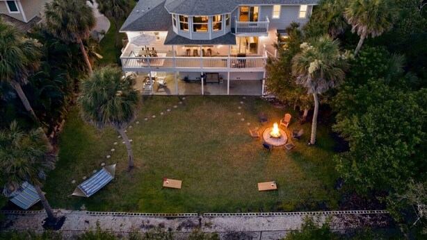 A large house with a circular deck, a fire pit, and a well-maintained lawn. - Mangrove Manor | Waterfront + Backyard Oasis (Seminole)