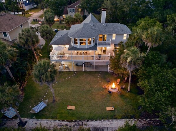 A large house with a circular deck, a fire pit, and a well-maintained lawn.