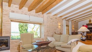 Un salon chaleureux avec un mur en pierre, des poutres apparentes, une cheminée, un canapé et une table basse.