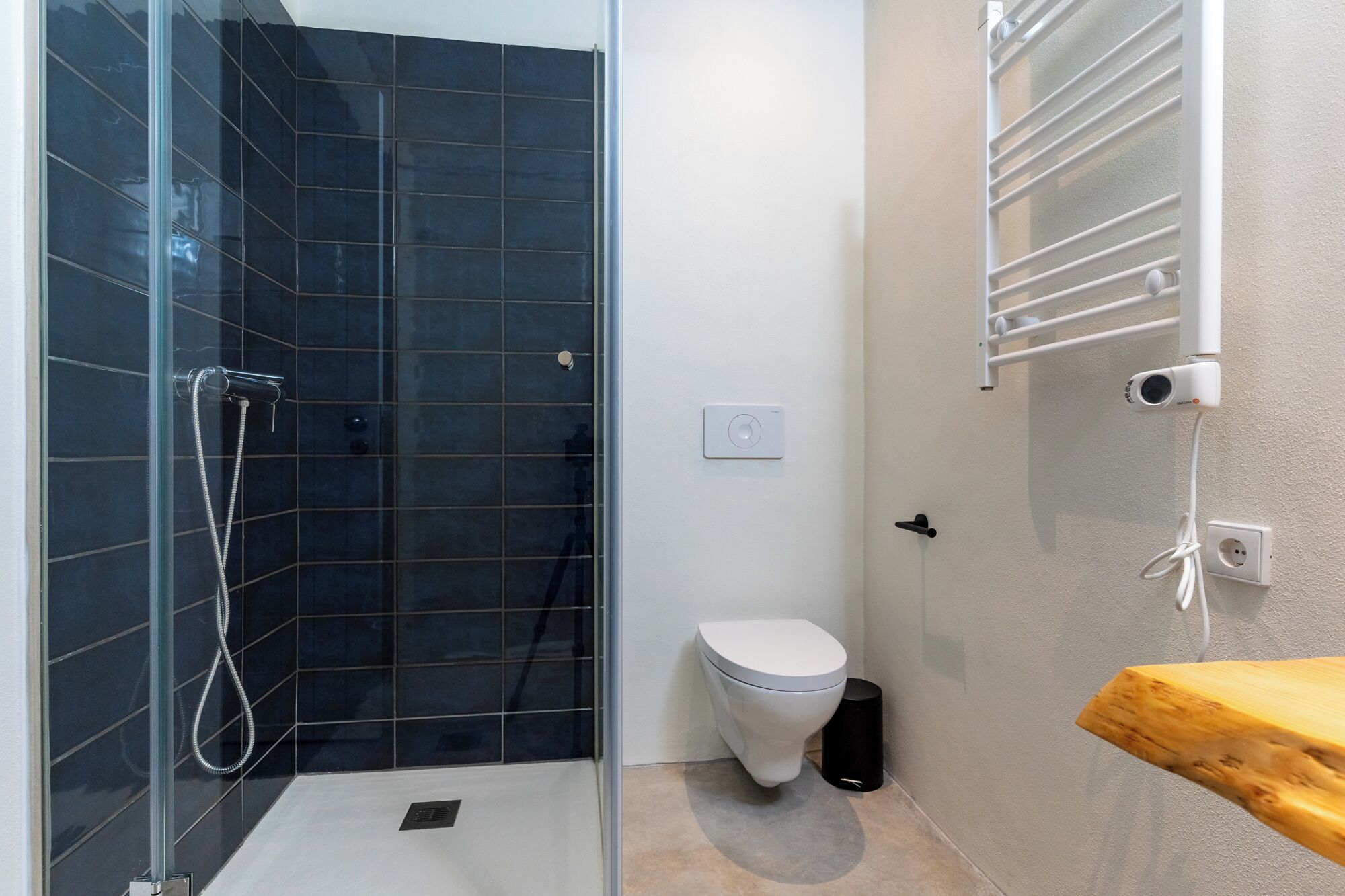 Une salle de bain moderne avec une douche à parois de verre, des toilettes et un meuble-lavabo en bois.