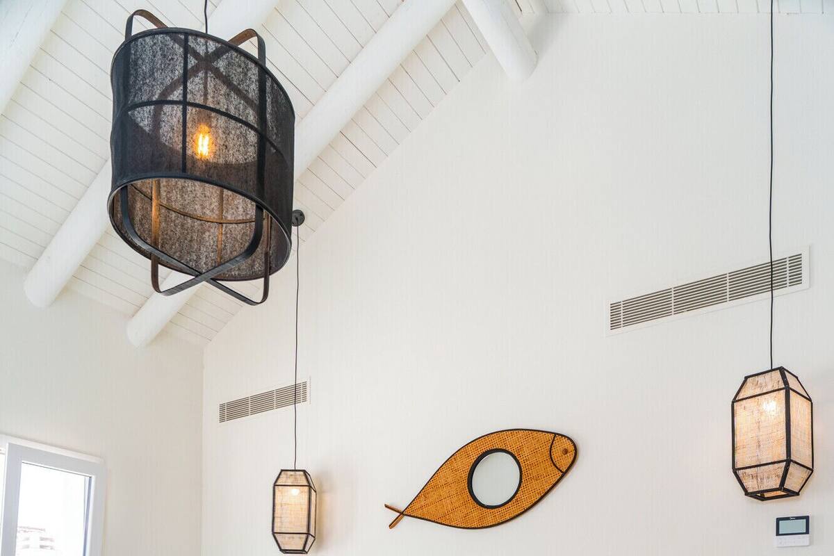 Ett sovrum med en säng, ett sängbord, en vägglampa och en dekorativ lampa i form av en fisk.