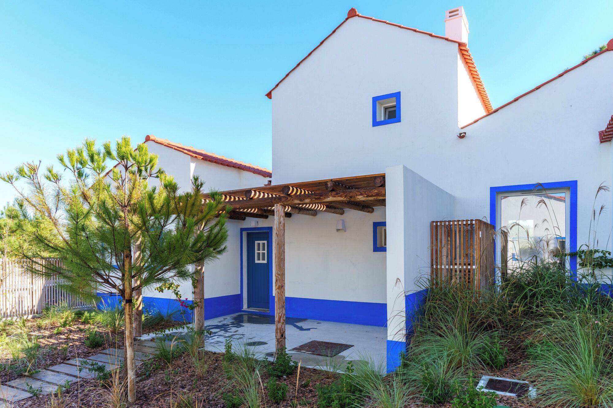 A white building with blue trim and a wooden pergola.