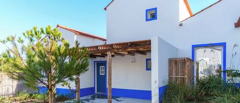 A white building with blue trim and a wooden pergola.