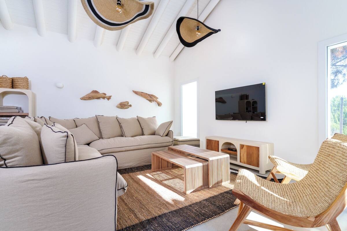 Ett modernt vardagsrum med en soffa, ett soffbord och en fåtölj, en platt-TV och dekorationer som hänger på väggen.