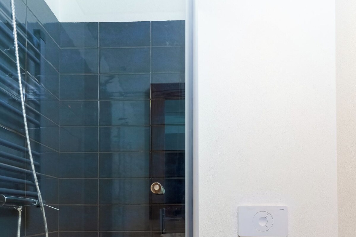 Ein modernes Badezimmer mit Duschkabine aus Glas, Toilette und einer an der Wand montierten Bedienkonsole.