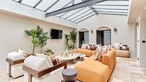A spacious indoor area with a high ceiling and skylight, furnished with sofas, chairs, and a coffee table.