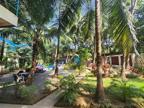 A resort with palm trees, outdoor seating, and a pool area. - La Perla Resort By Circle Hotels&Resort (Morjim)