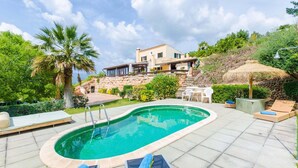 Ein Pool mit Liegestühlen, eine Steintreppe und ein Haus im Hintergrund.