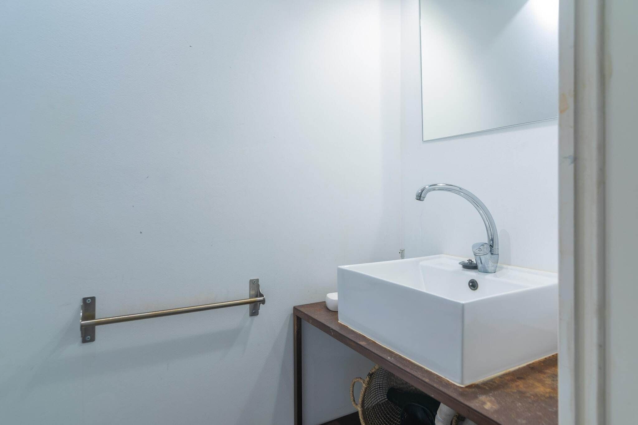Ein Badezimmer mit Waschbecken, Spiegel und einer Haltestange.
