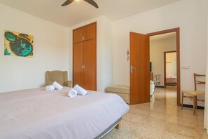 A hotel room with a bed, a wooden wardrobe, a chair, and a painting on the wall.