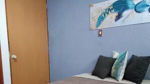 Un dormitorio con cama, pared azul y puerta de madera.