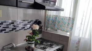 Una cocina compacta con armarios oscuros, un lavamanos de acero inoxidable y una estufa a gas.