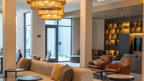 Un vestíbulo moderno con un sofá beige grande, mesas redondas y una estantería.