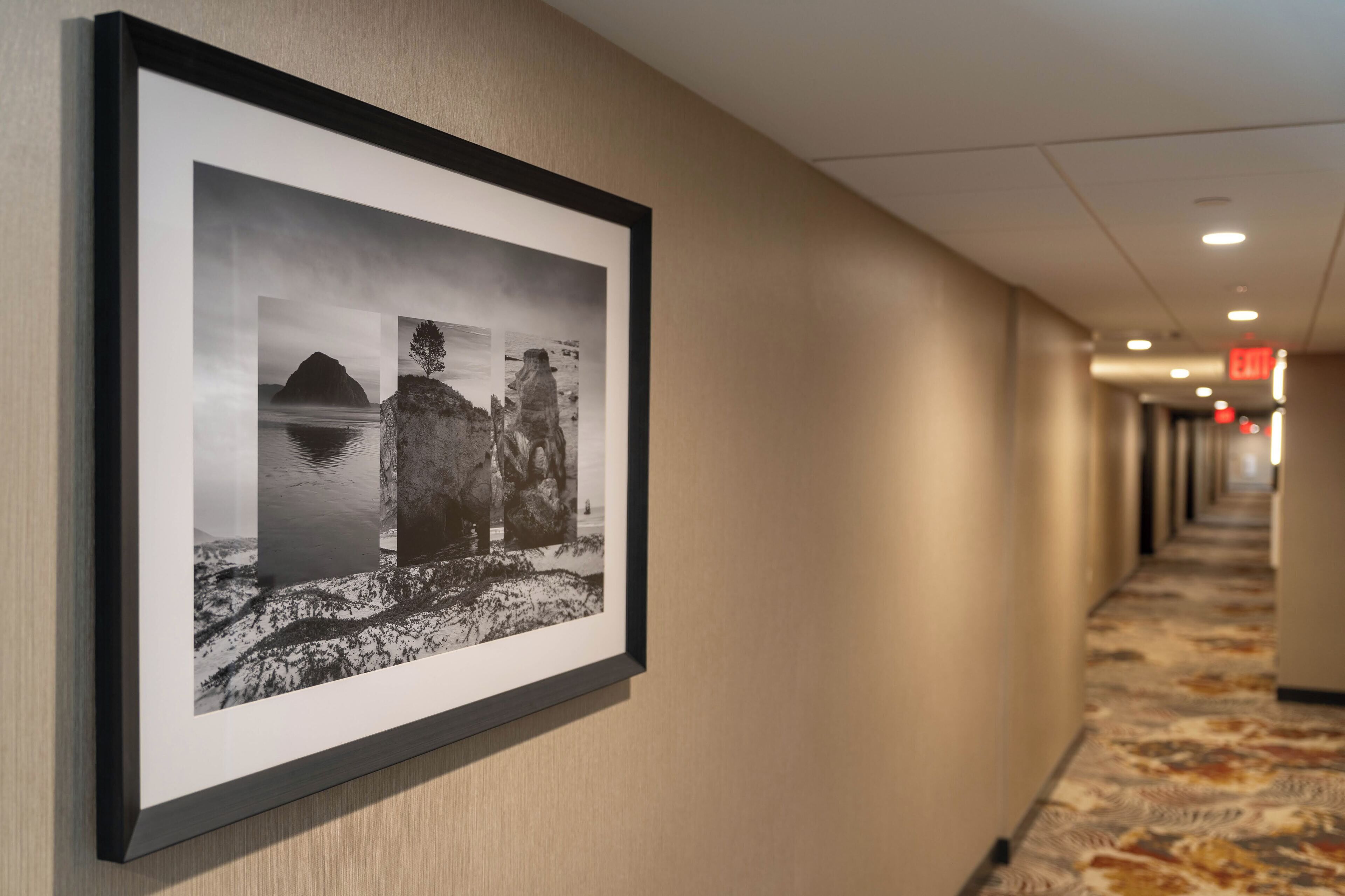 A hallway with a framed black and white photograph of a mountainous landscape on the wall.