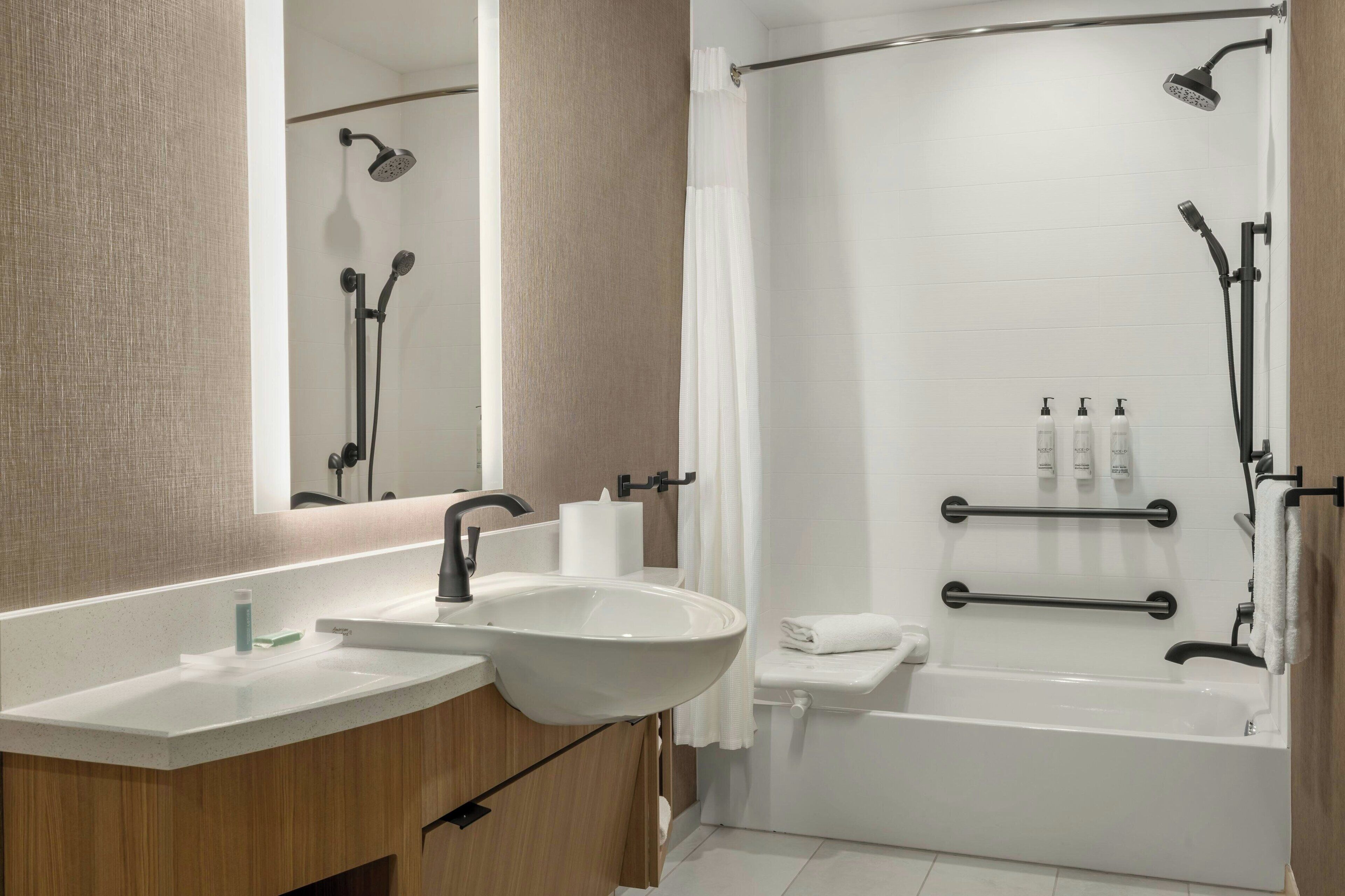 A modern bathroom with a large sink, mirror, and shower area.