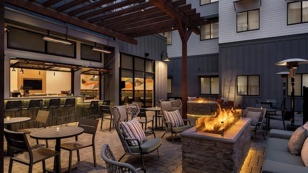 Un espacio al aire libre con patio, chimenea, asientos y barra.