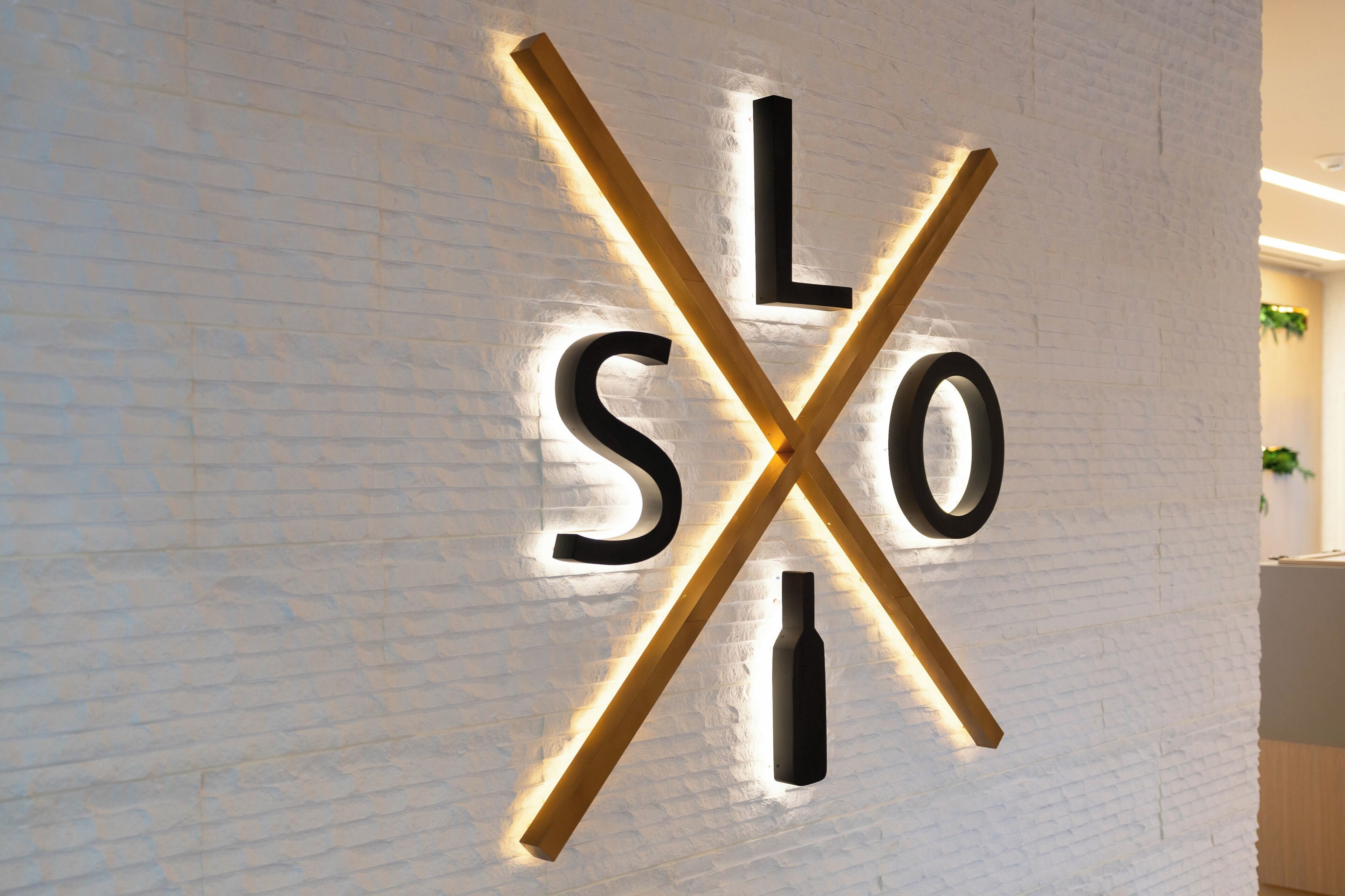 A wall with illuminated letters spelling "LOX" and a wooden cross.