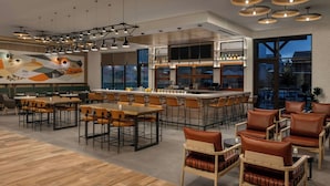 Un interior de restaurante moderno con varias zonas de comedor, un bar y una cocina visible a través de las ventanas.