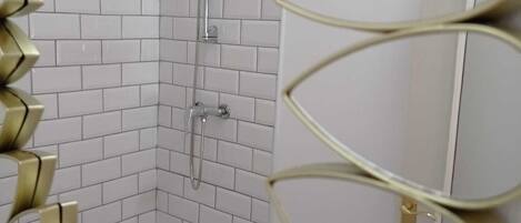 Un baño con paredes de azulejos blancos, una ducha y un inodoro.